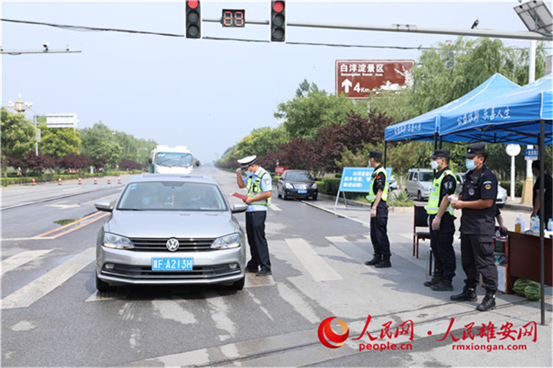 雄安新區安新縣對進出車輛實施臨時交通管制，交警正在檢查過境車輛的通行証，並測量體溫。李雪晴 攝