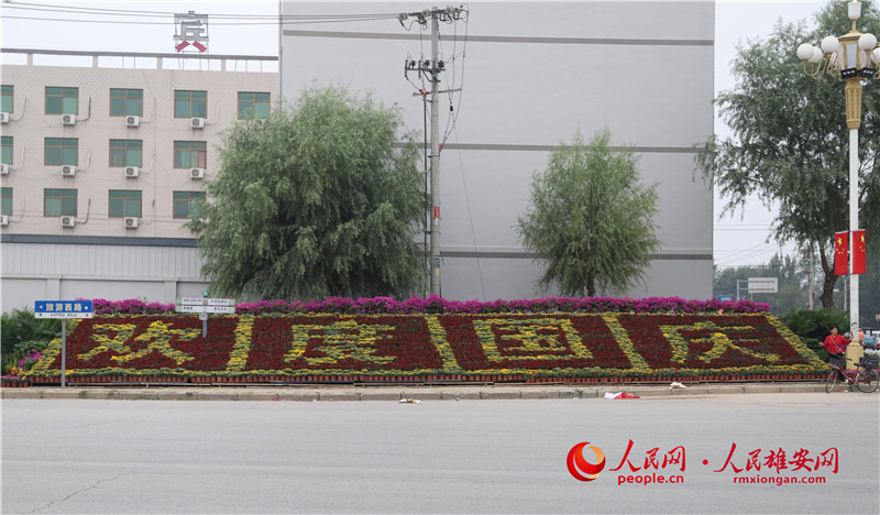 雄安新區安新縣旅游路和建設大街交叉口“歡度國慶”的花卉景觀，引來不少居民駐足合影。李晰雅、韓笑/攝