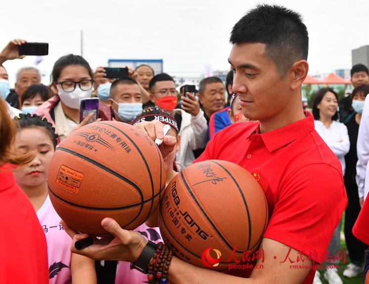 奥运冠军邢傲伟在向现场青少年赠送签名篮球。人民网 宋烨文摄
