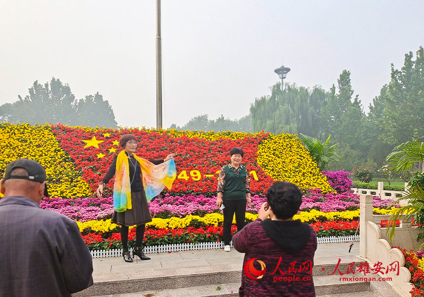 雄安新区雄县的广场上，游人正在和国庆花坛合影。朱峙委摄