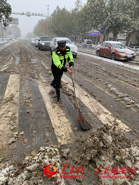 雄縣交警在風雪中清理道路積雪。陳達攝