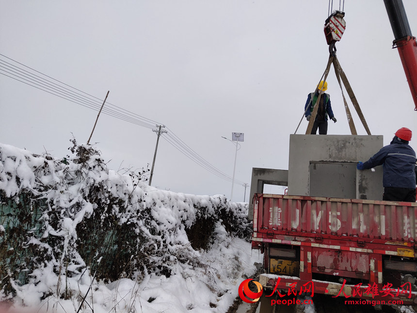 中铁三局启动区道路机电一标项目部在雪中进行预制电缆井卸车就位作业。雄安集团基础建设公司供图
