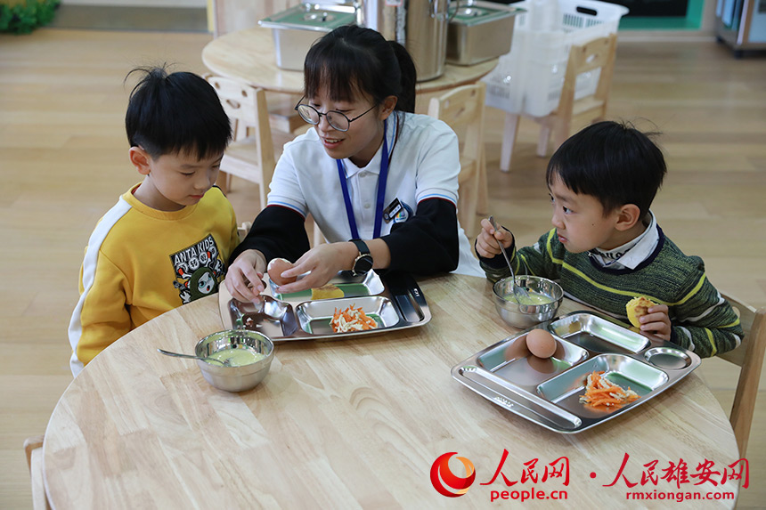 圖為雄安容和雙文幼兒園開園第一天，老師在教孩子剝雞蛋。人民網 王紅攝 