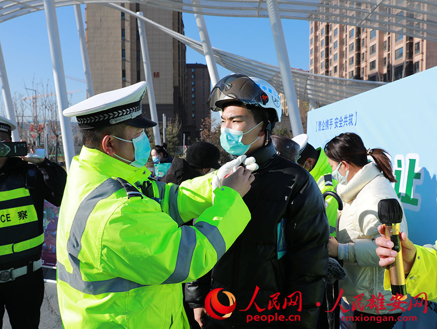 图为交警为回答对问题的市民佩戴安全头盔。人民网 王红摄