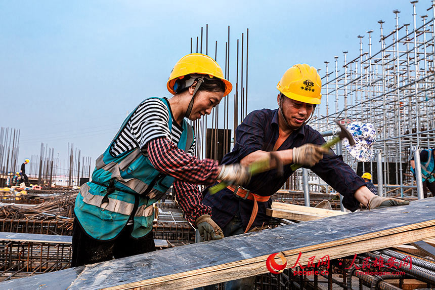 來自重慶的張明、王菊夫婦都是木工，二人配合默契，安裝澆筑模板得心應手。