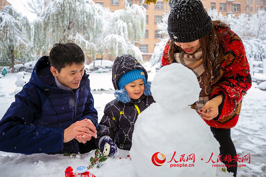 大雪過后，小朋友正在和父母一起開心地堆雪人。齊鑫攝