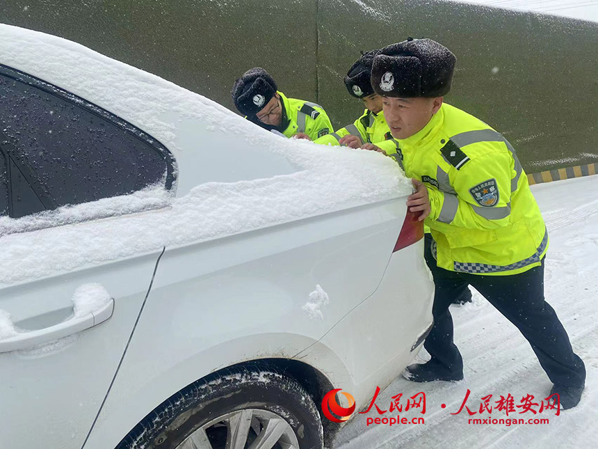 雪中正在幫助群眾推車的警察。王世恆攝