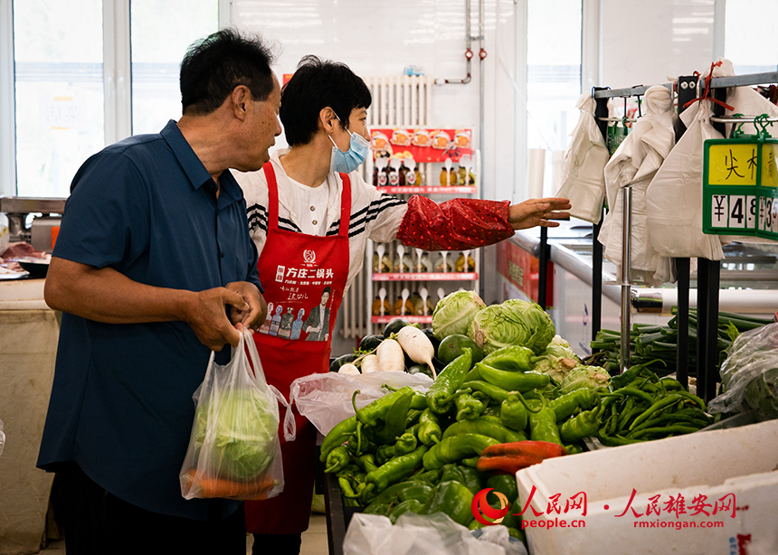 菜店内，工作人员正在为顾客提供帮助。出门就是菜店，吃饭不发愁，成为容东片区居民的日常。人民网 宋烨文摄