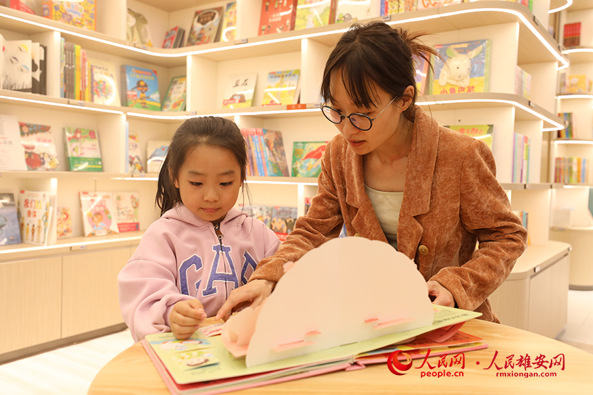 4月22日，在雄安新区新建片区的书店里，一名家长正在陪孩子阅读。人民网记者 李兆民摄