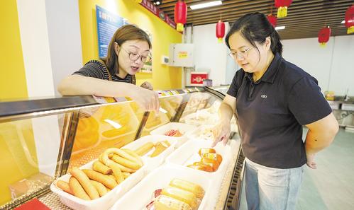 7月11日，位于雄安·老字号商业街的中华老字号天津“迎宾”牌肉制品门店内，顾客正在挑选火腿。本报见习记者 李畅摄