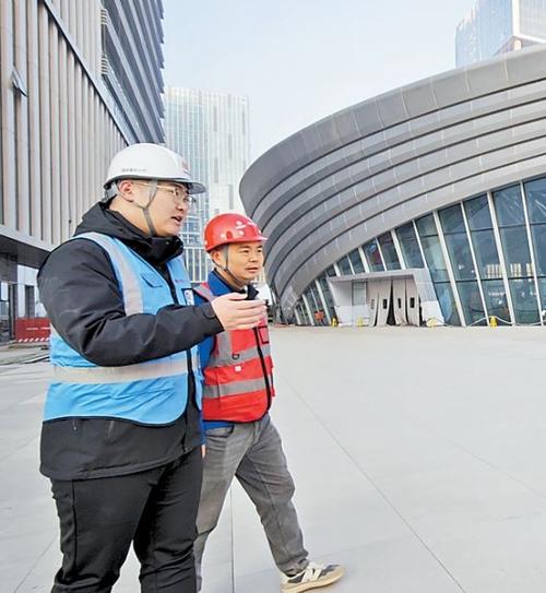 近日，在雄安国贸中心及京雄快线项目现场，雄商置业公司工程管理部工作人员许文康（左）与施工人员进行早班交流。 本报记者 曹铮摄