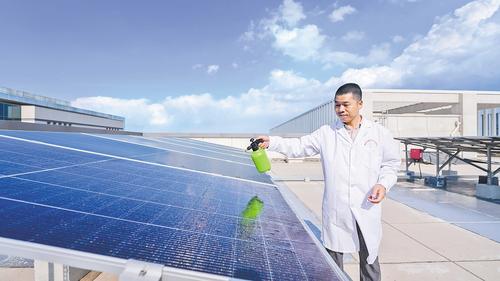 6月4日，雄安科創中心C座樓頂，雄安百城百潤納米科技有限公司首席技術官周明正在向光伏板噴洒太陽能光伏提效涂層材料。 本報記者 李 暢攝