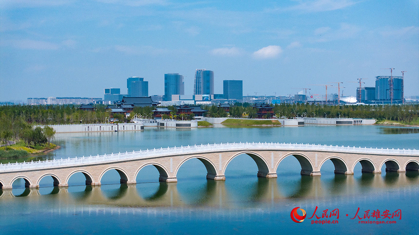 雄安新区启动区，多孔石拱桥横跨碧波，远处现代化建筑群崛起，呈现“水城共融”画卷。人民网记者 李兆民摄