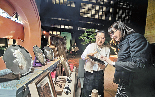 10月24日晚，“雄安之約”河北特色非遺展示活動在2026全球治理論壇（雄安）會場外舉行。圖為河北省級非遺代表性項目郭氏鐵板浮雕代表性傳承人郭墨涵（左）向外賓介紹非遺作品。本報記者 王 偉攝
